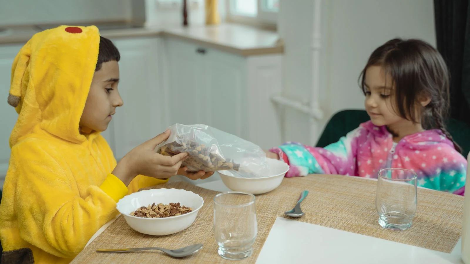 Kids in bright costumes sharing breakfast at a cluttered family table