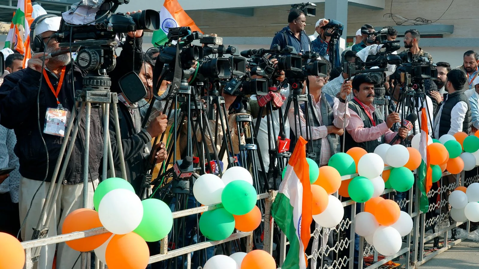 Press photographers crowding a scene with cameras, the earned coverage that syndicates onward