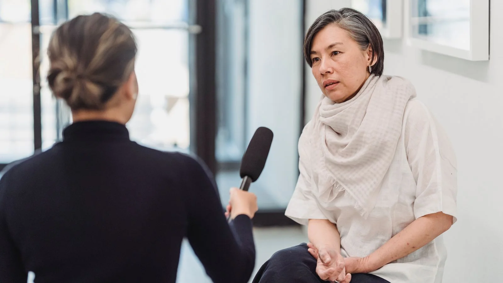 A local journalist taking notes while interviewing a woman in a professional setting