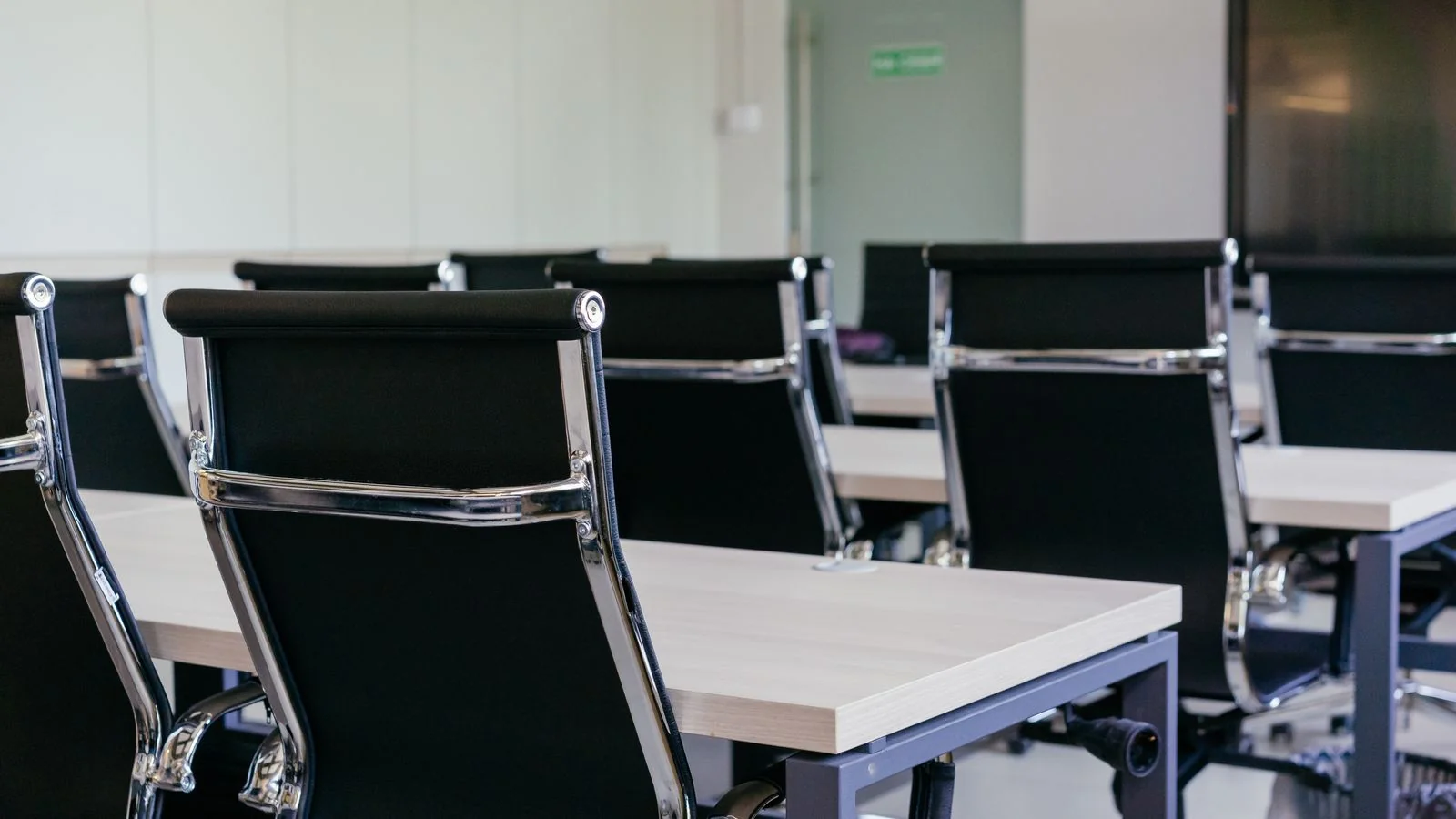 An empty conference room with rows of black chairs, set up and waiting for an audience that may not include press.