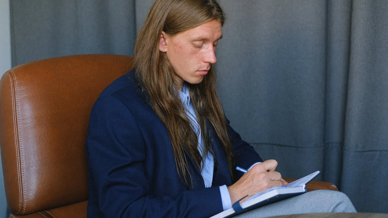 A journalist sitting at a table taking handwritten notes, the way coverage often happens away from the venue.