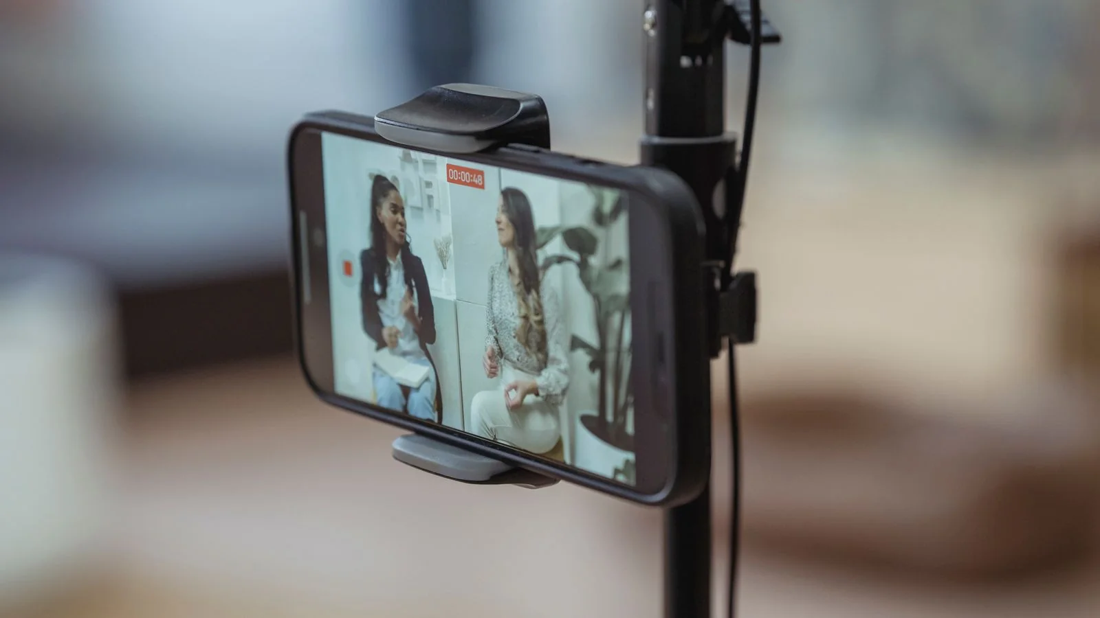 Phone mounted on a tripod recording two women talking, the recorded conversation as the unit of value