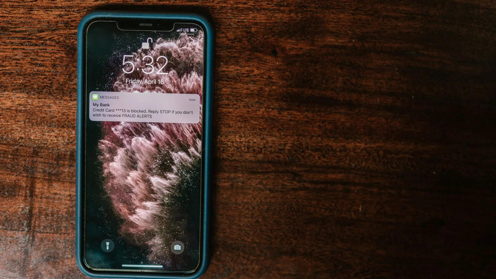 Smartphone lying on a wooden surface displaying an incoming notification alert on its lock screen