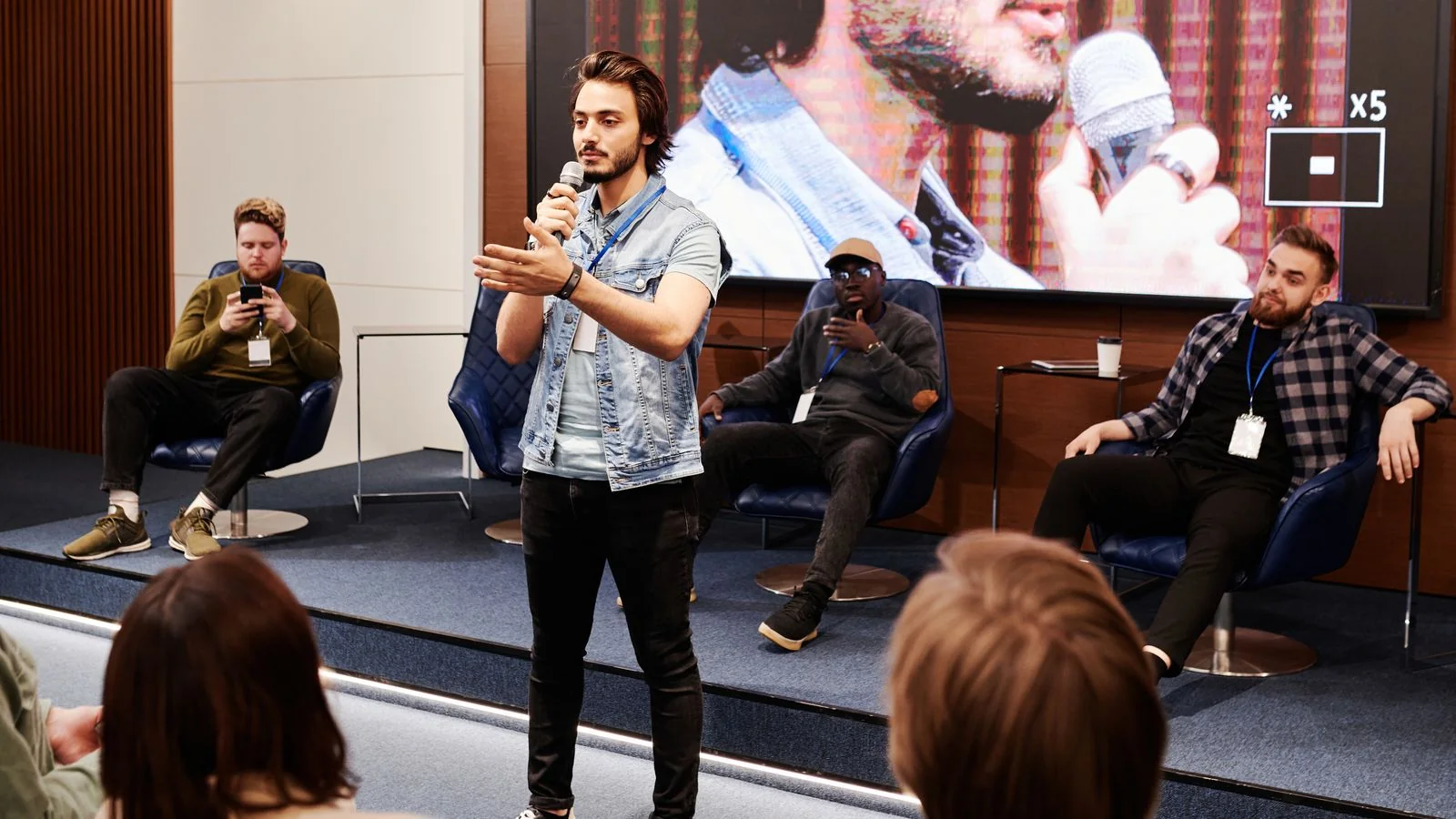 Confident speaker holding a microphone while engaging an audience at an indoor conference