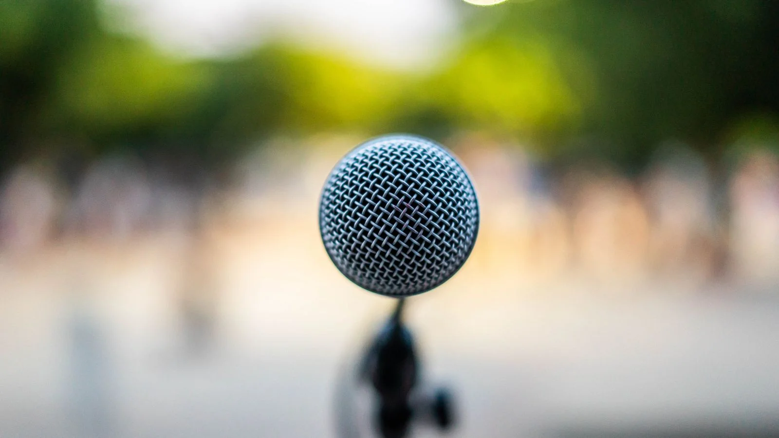 Microphone on a stand under a spotlight on stage, the slot that gets booked long before the event
