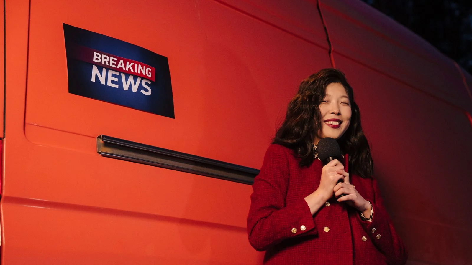 A reporter with a microphone preparing for a live broadcast outside