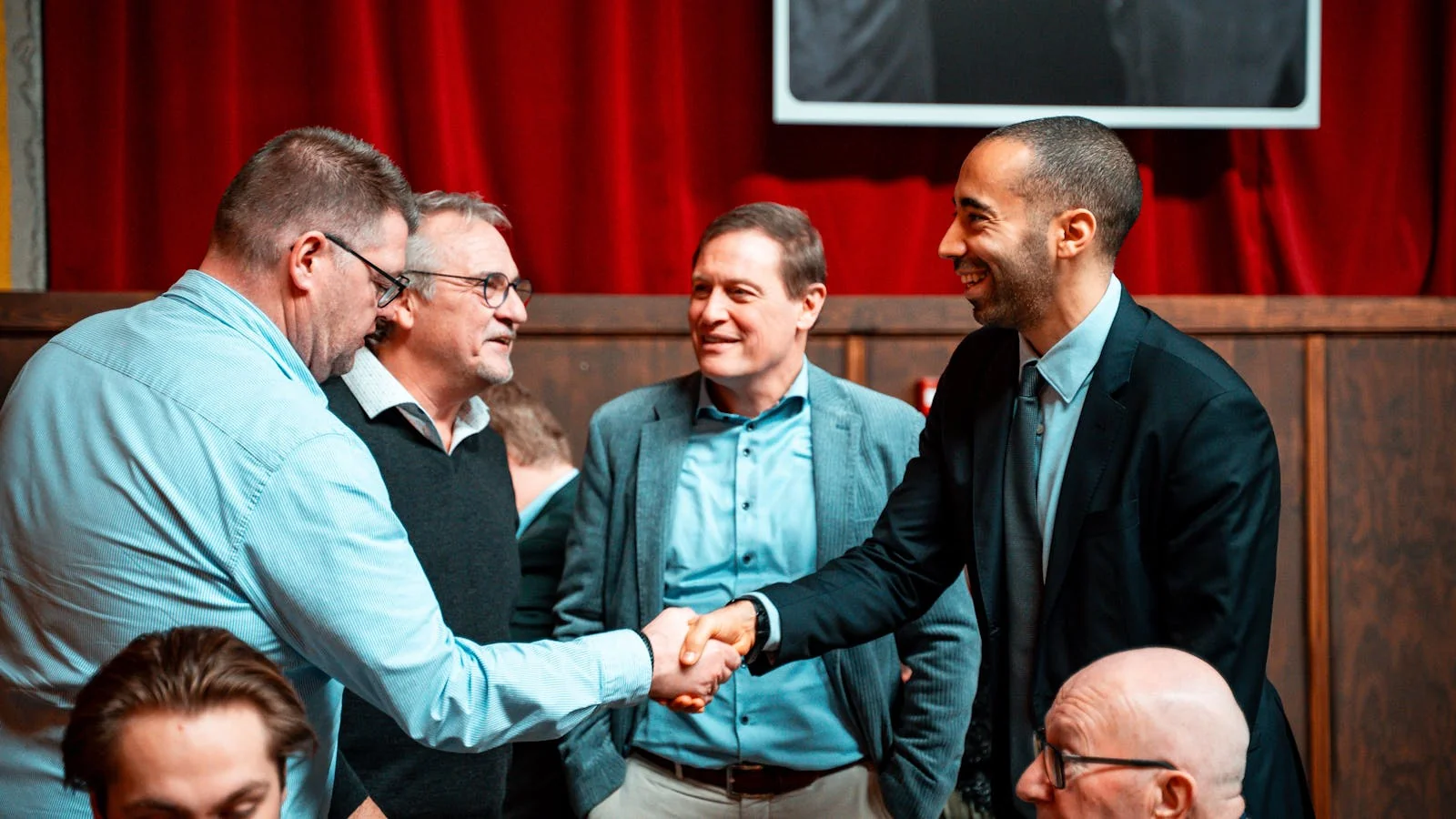Five business professionals shaking hands during a meeting, the kind of networking moment that turns a single speaking gig into an invitation to the next one