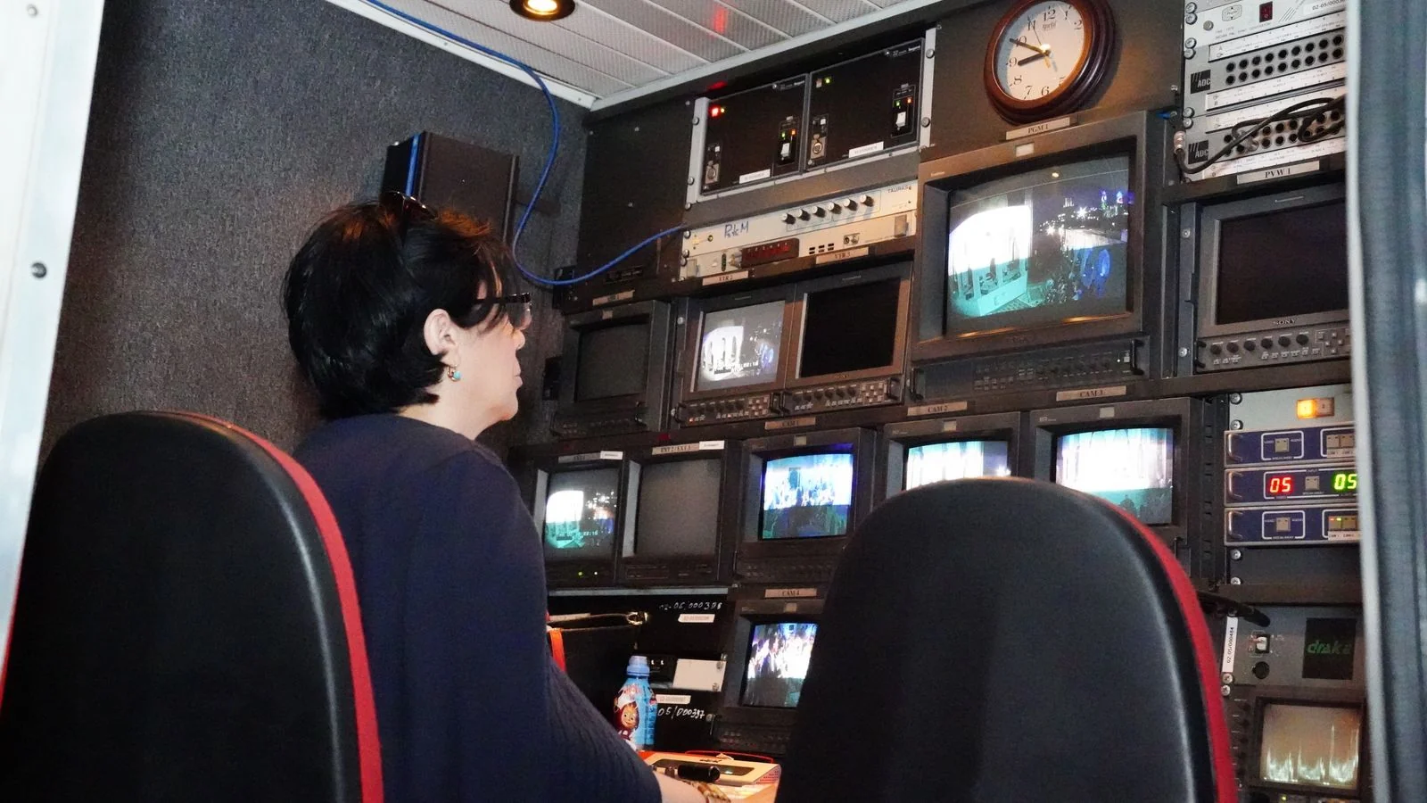 Inside a television broadcast control room with multiple monitors and equipment
