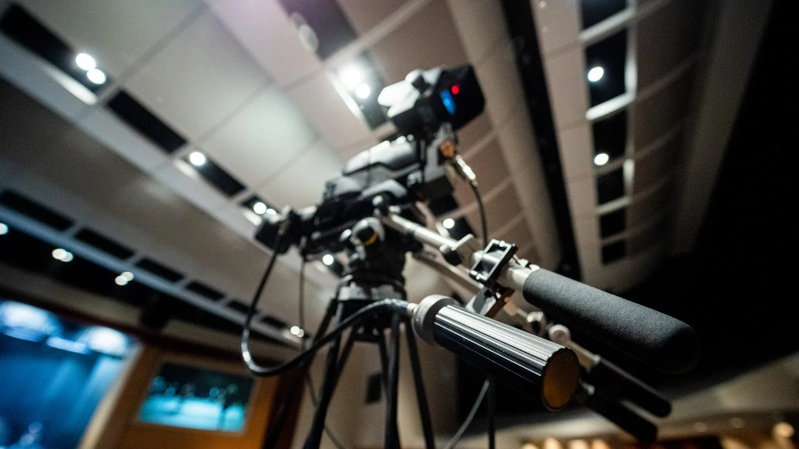 A professional video camera on a tripod in a darkened studio, the kind of rig that frames a live cable news segment.