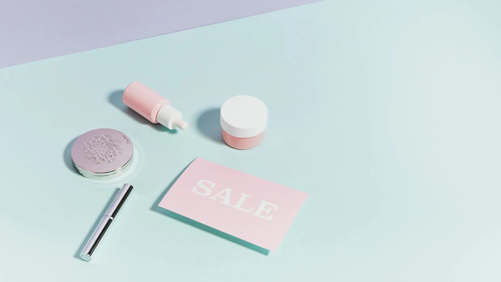 A flat lay of pastel pink beauty products arranged on a light background