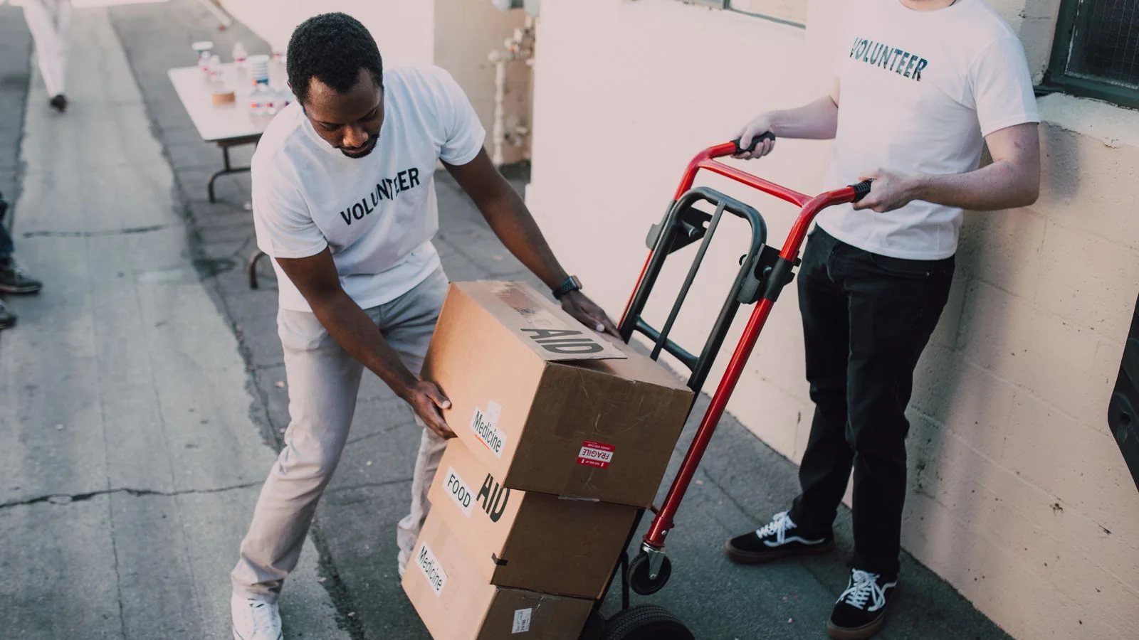 Volunteers carrying boxes of donated supplies at a neighborhood charity event