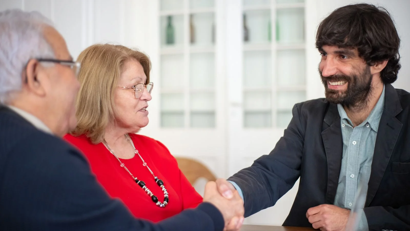Two professionals shaking hands across a desk after a coaching consultation