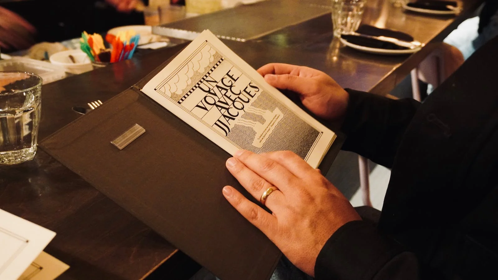 Guest reading a restaurant menu under warm lighting, the dining-room beat reporter's natural habitat