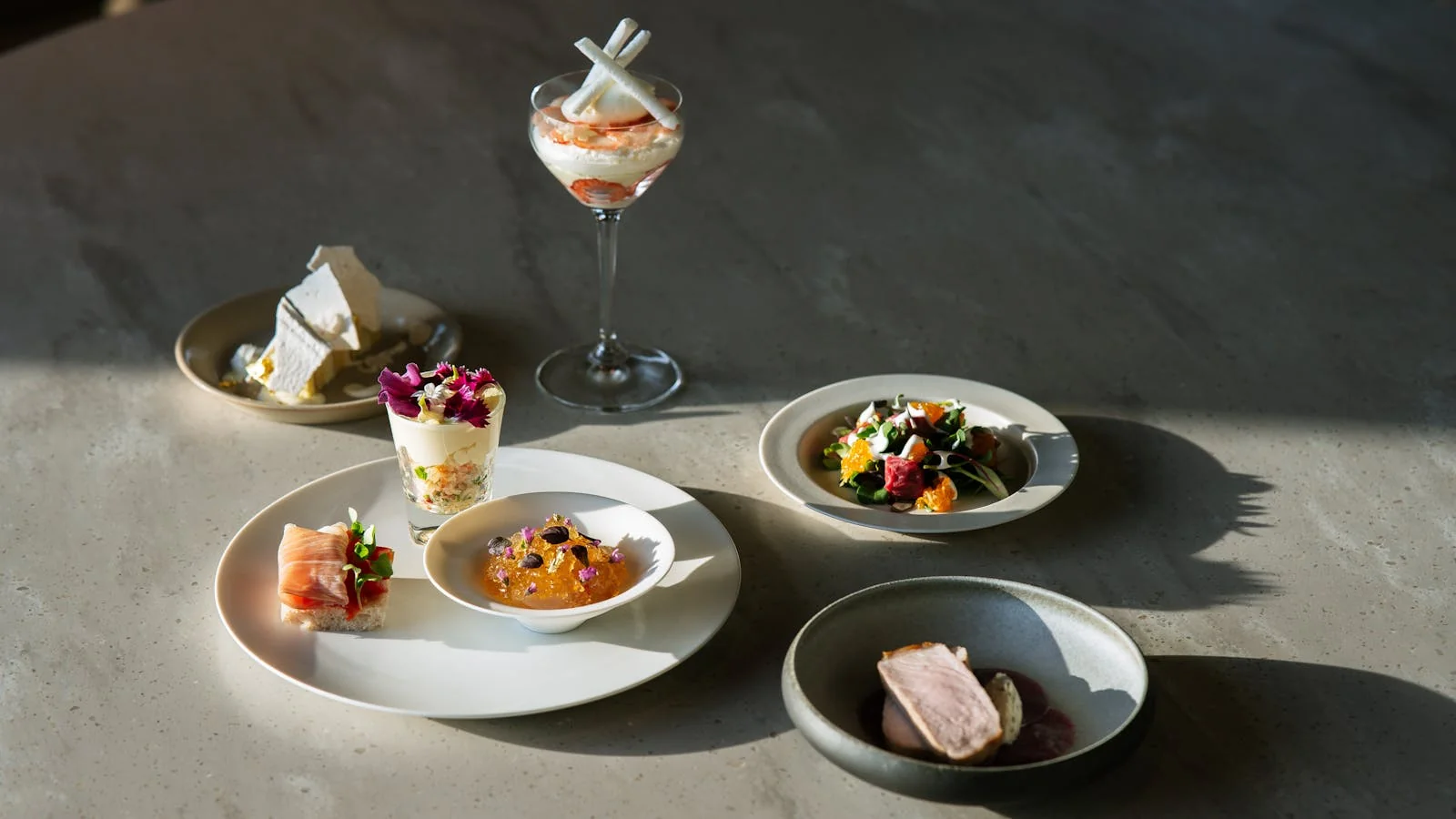 Plated tasting course on a linen-set table, the kind of visual that gets food editors to open a pitch
