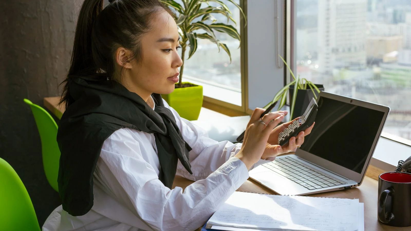 A woman calculating finances in a bright modern office, the bookkeeper reporters want to quote.