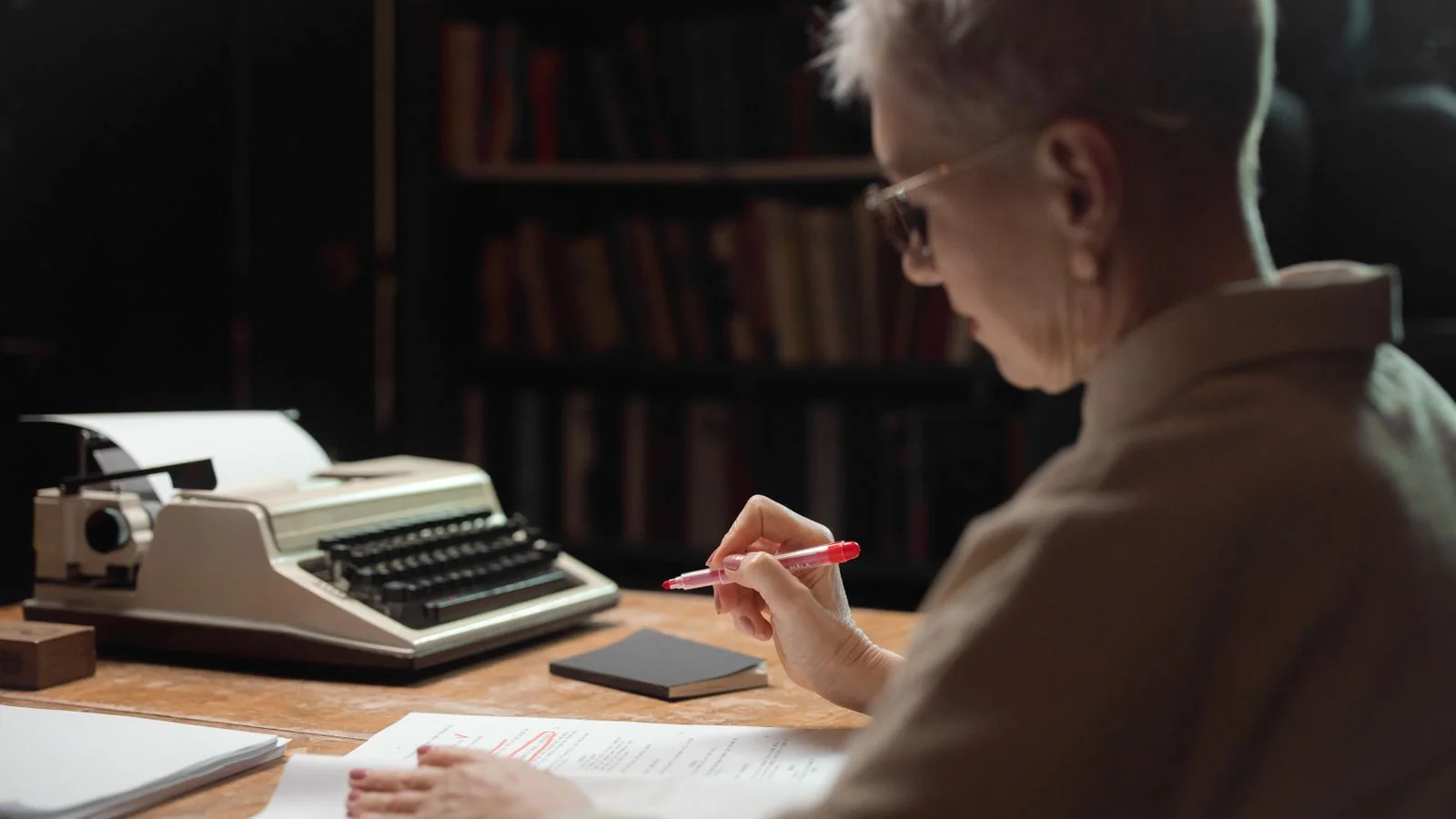 An editor marking up a story draft at a wooden desk.