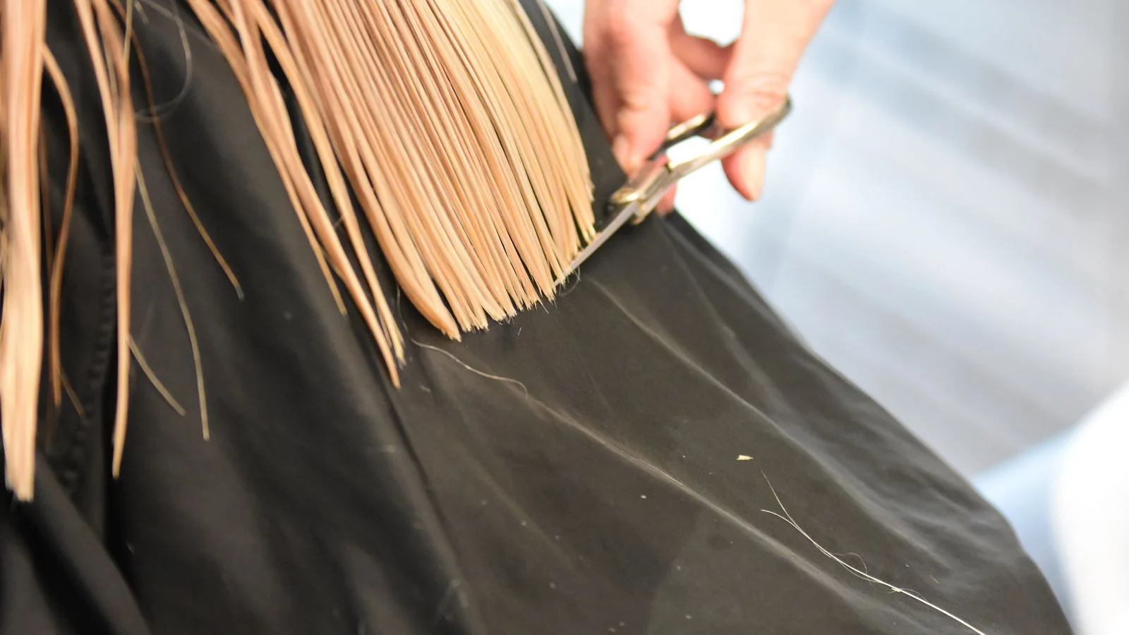 A stylist cutting a client's hair with scissors in close-up, the daily work that turns into a business-desk story