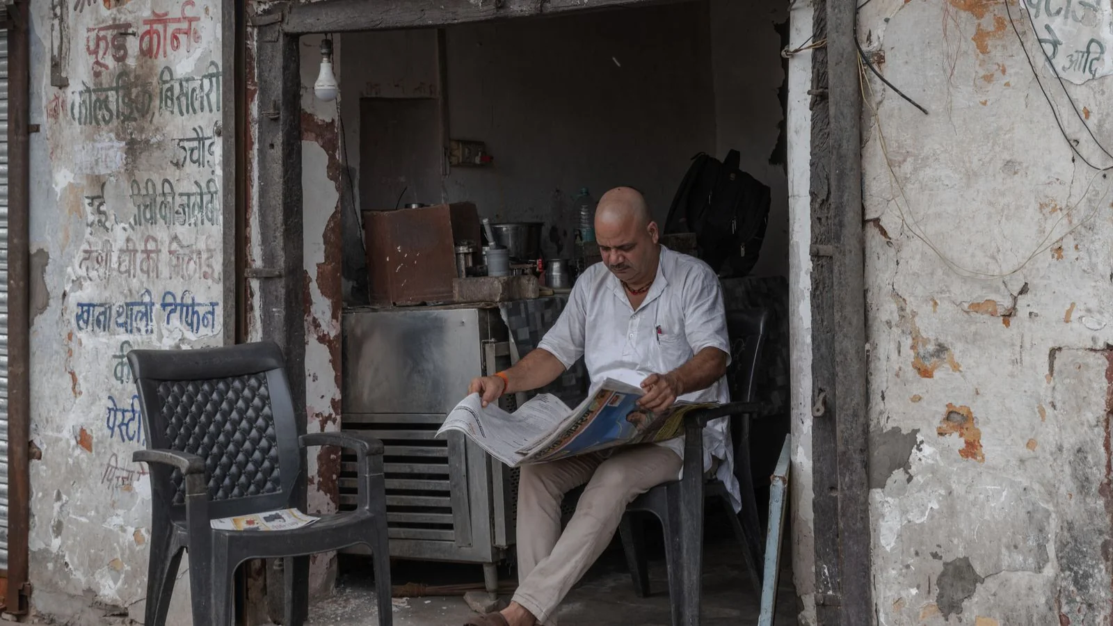 A man reading a newspaper outside a rustic cafe, the local reader who has never seen a surveyor quoted.