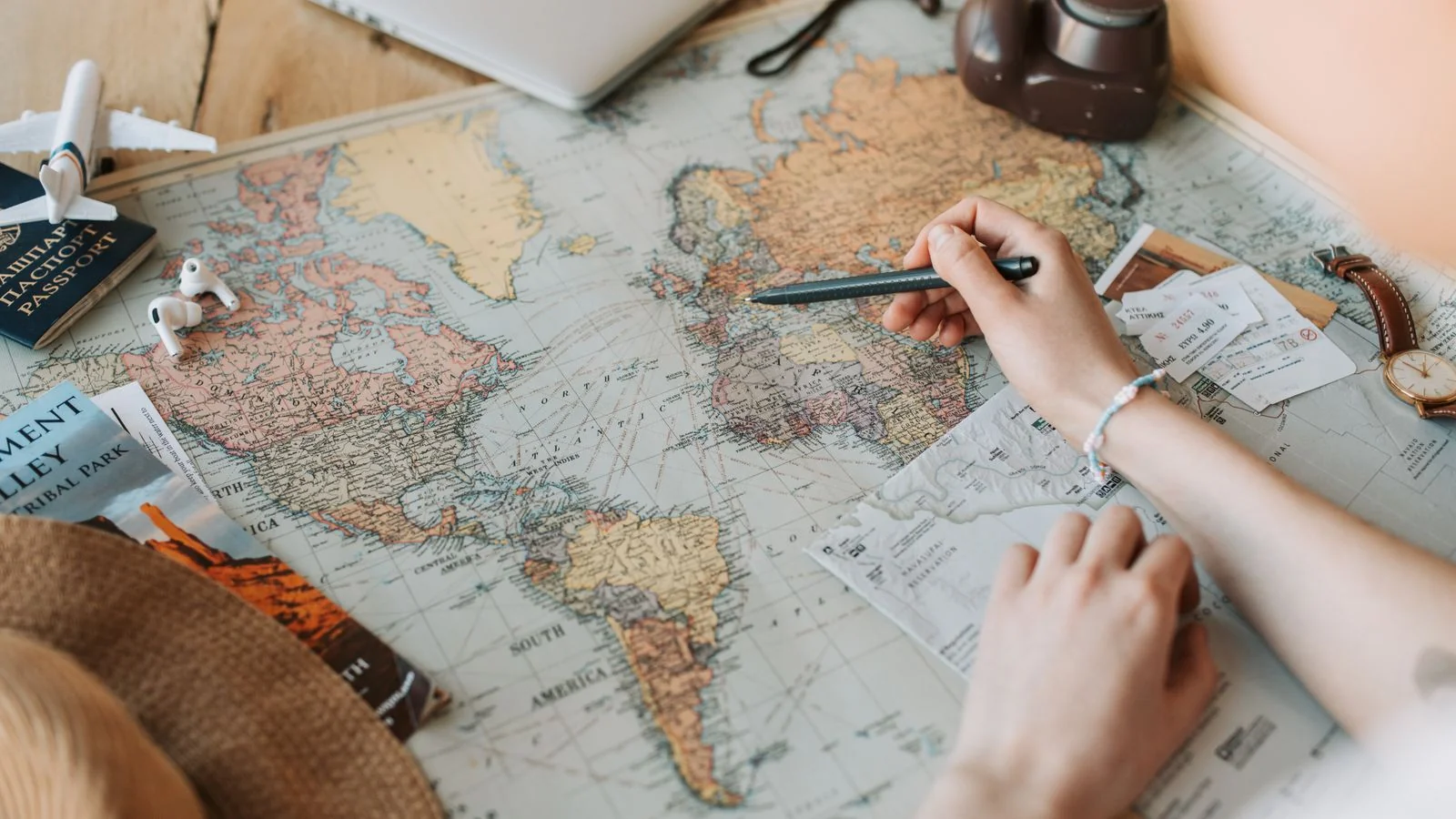 Hands marking destinations on a world map beside a passport, the ambition behind every enrollment form