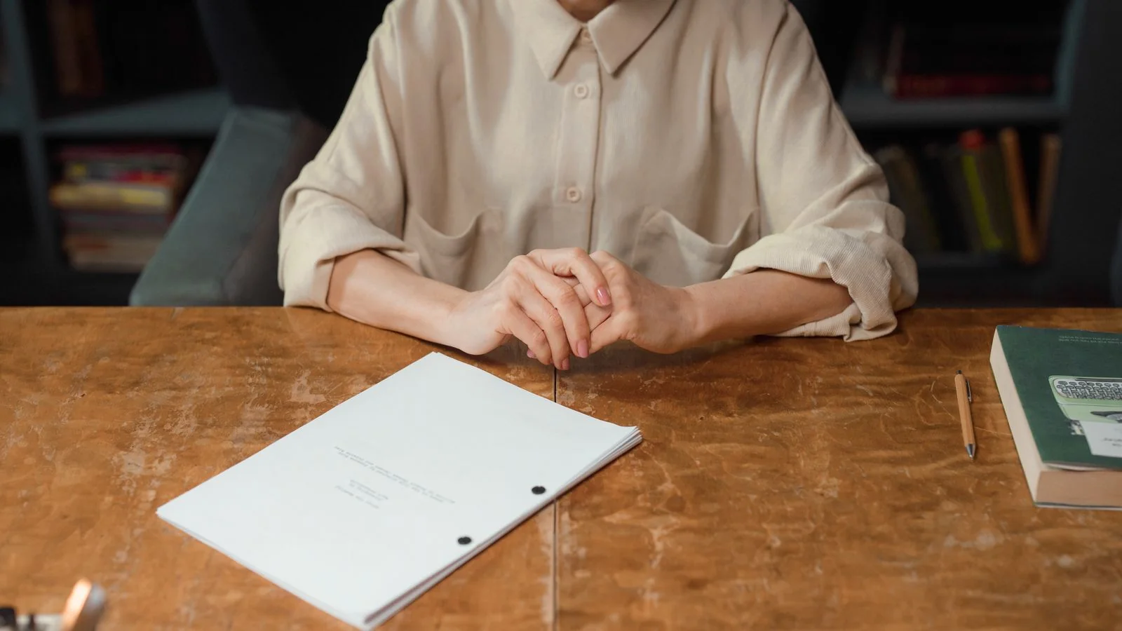 A woman at a wooden desk reviewing a manuscript, where a pitch either survives or does not