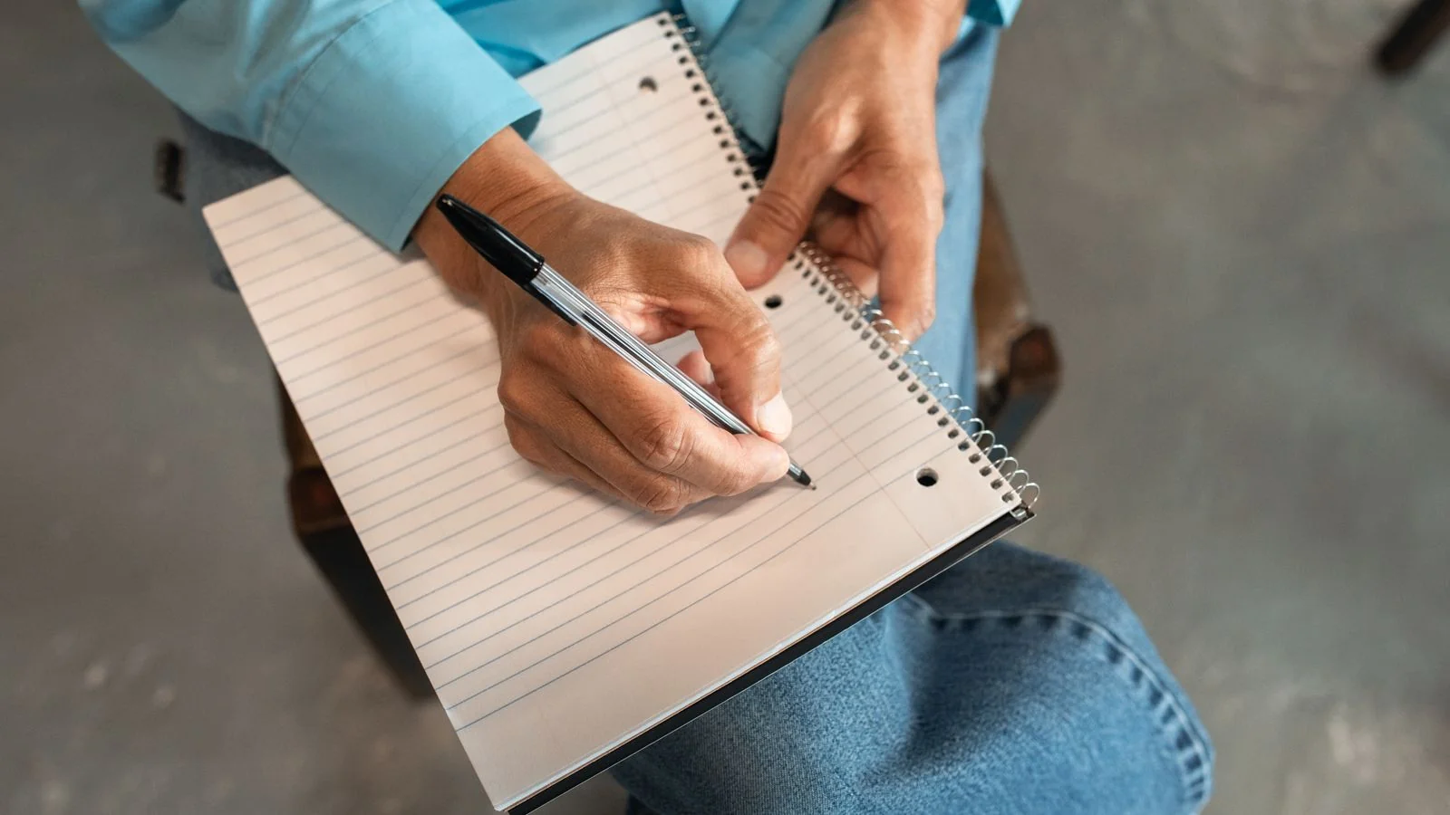 A reporter taking notes by hand during an interview
