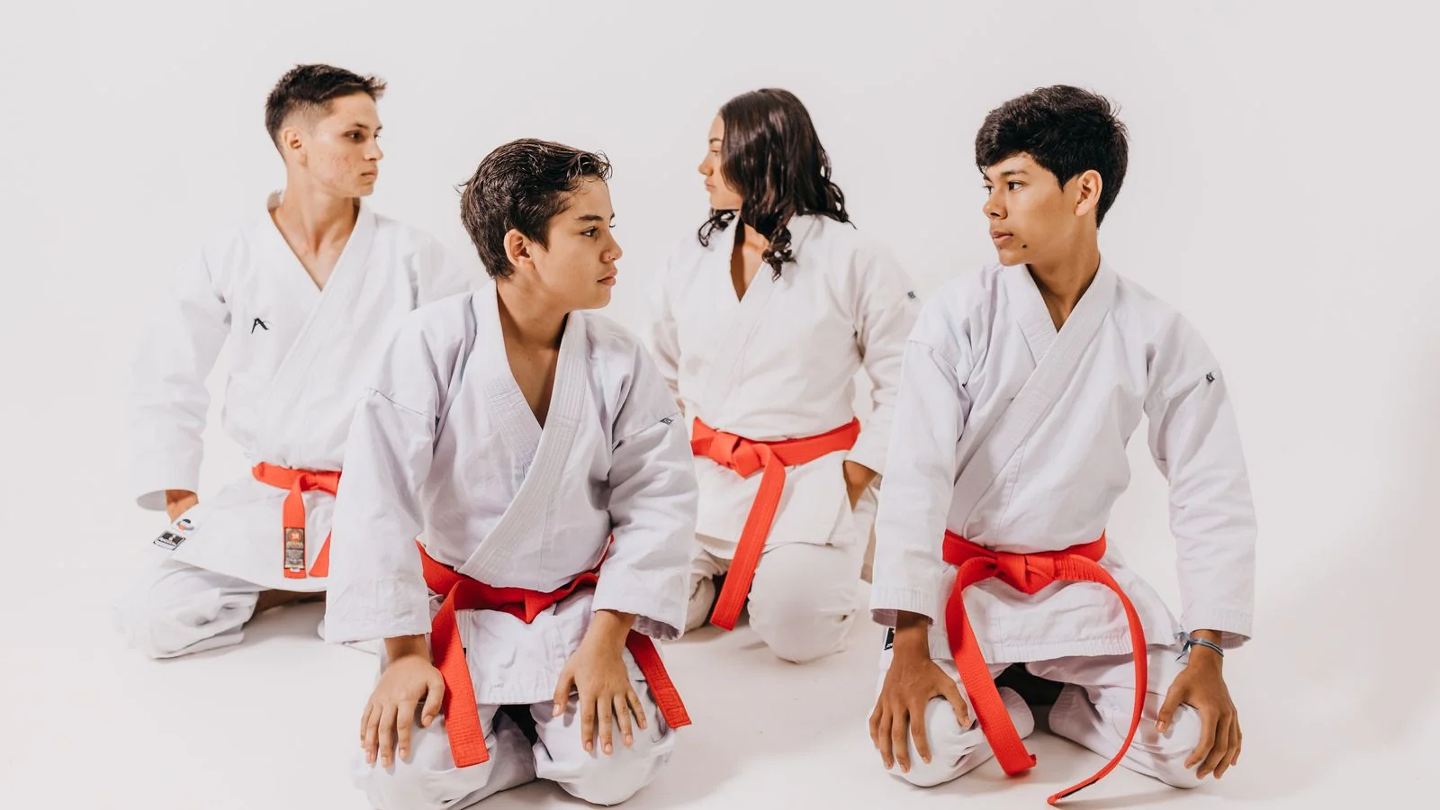 Teenagers in karate uniforms sitting together before class