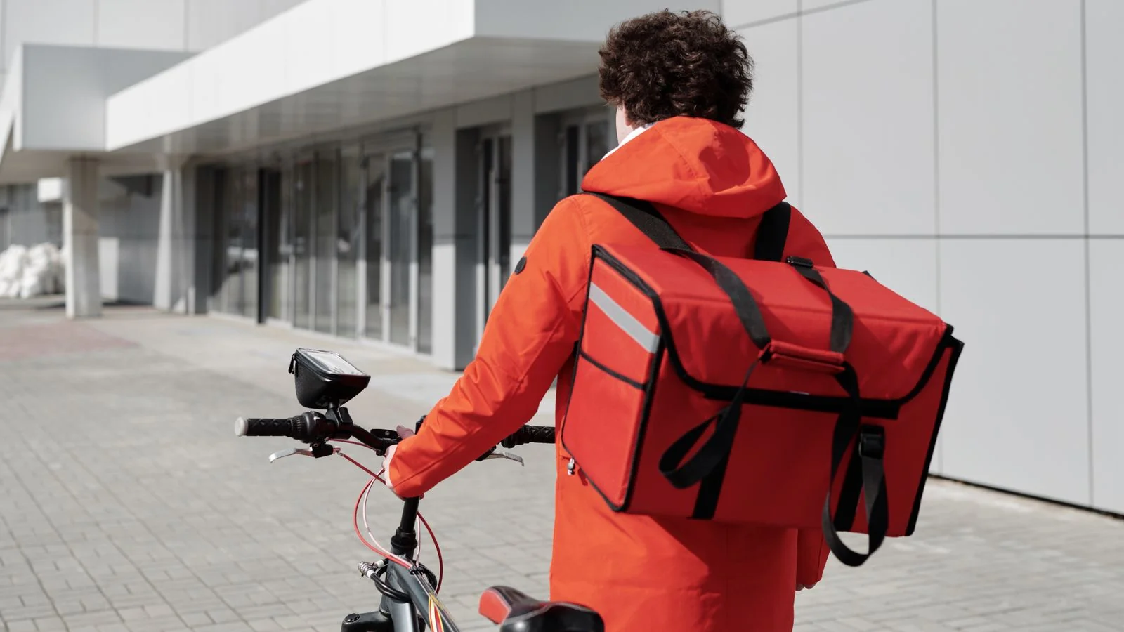 A delivery courier carrying an insulated bag, the logistics layer that is the actual business.
