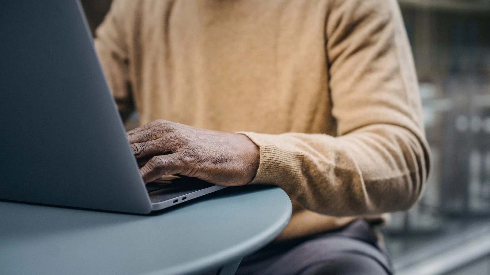 A journalist typing a story on a laptop in a busy newsroom on deadline