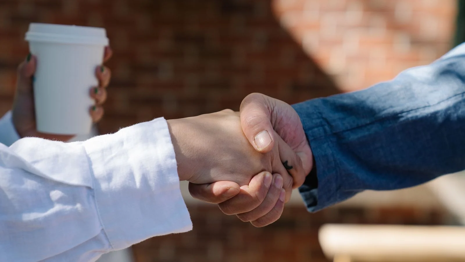Two people shaking hands at a local business meeting, the handshake that earns repeat coverage