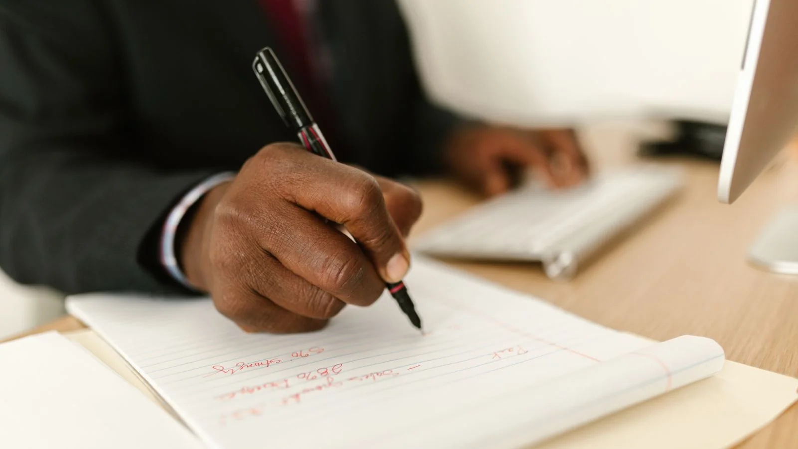 A person writing notes in a notepad at a desk, working through a pitch.