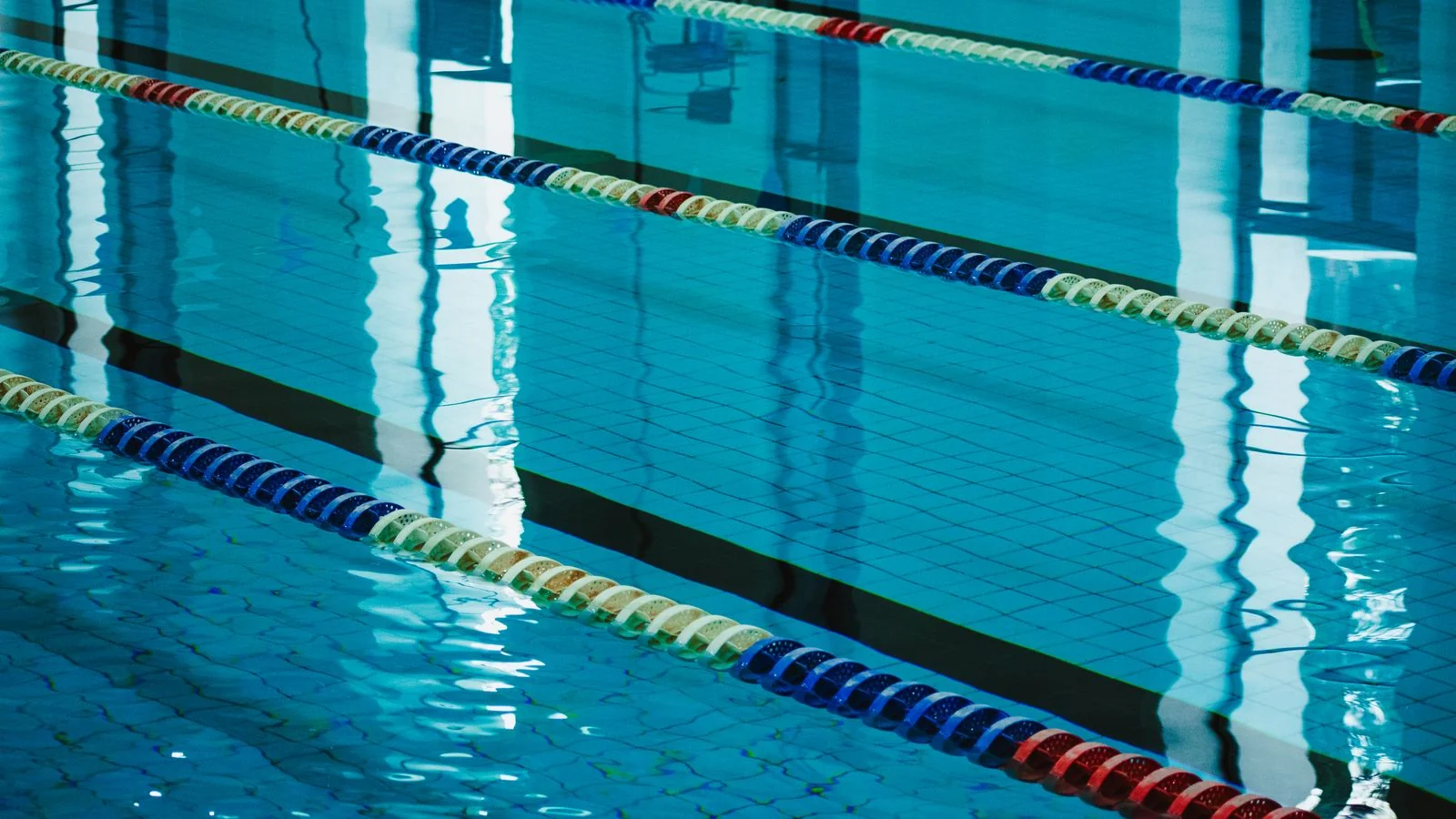 Empty indoor pool lanes reflecting light before the first lesson of the day