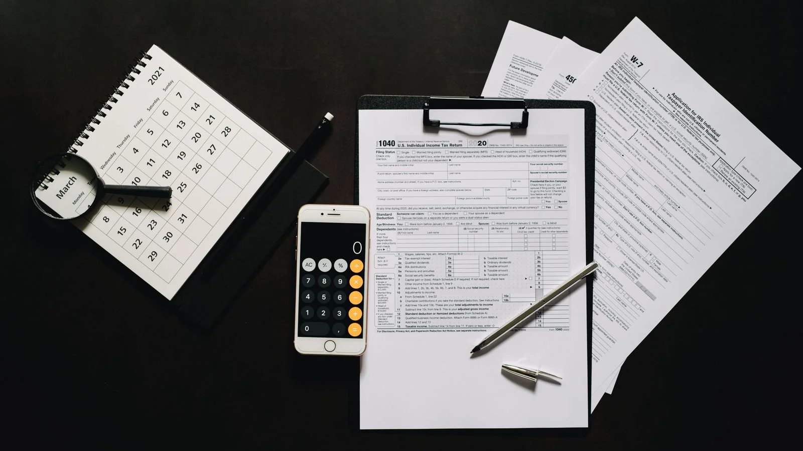 A calendar and tax forms arranged on a wooden desk.