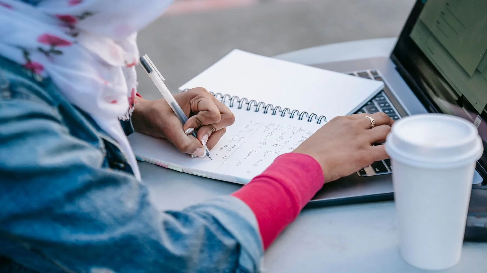 A reporter taking notes at a laptop while working on a story.