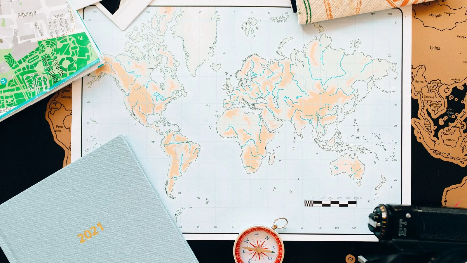 A flat lay of a world map, compass, and planner, the craft everyone assumed software replaced.