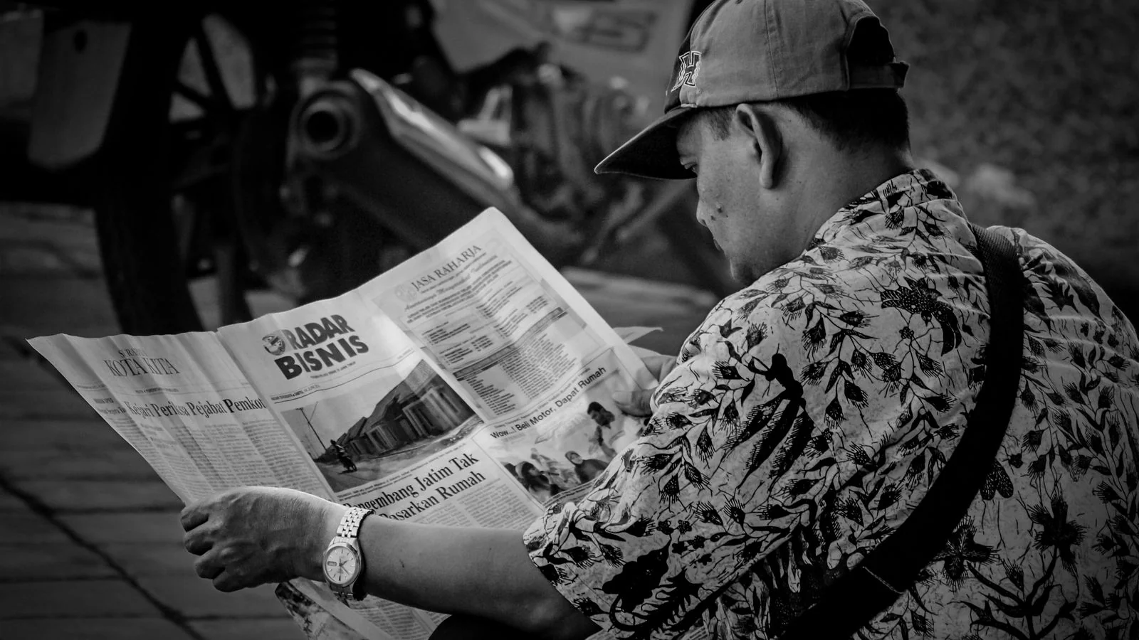 A man reading a newspaper outdoors, the local desk that runs the yoga story nobody pitched them