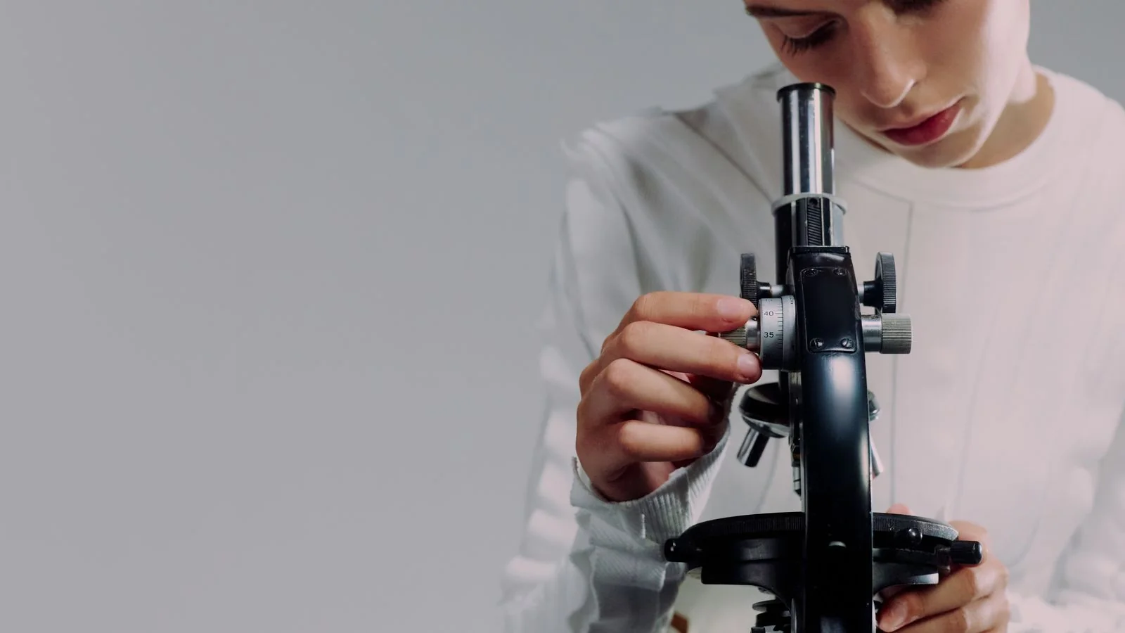 A researcher examines samples through a microscope in a modern lab