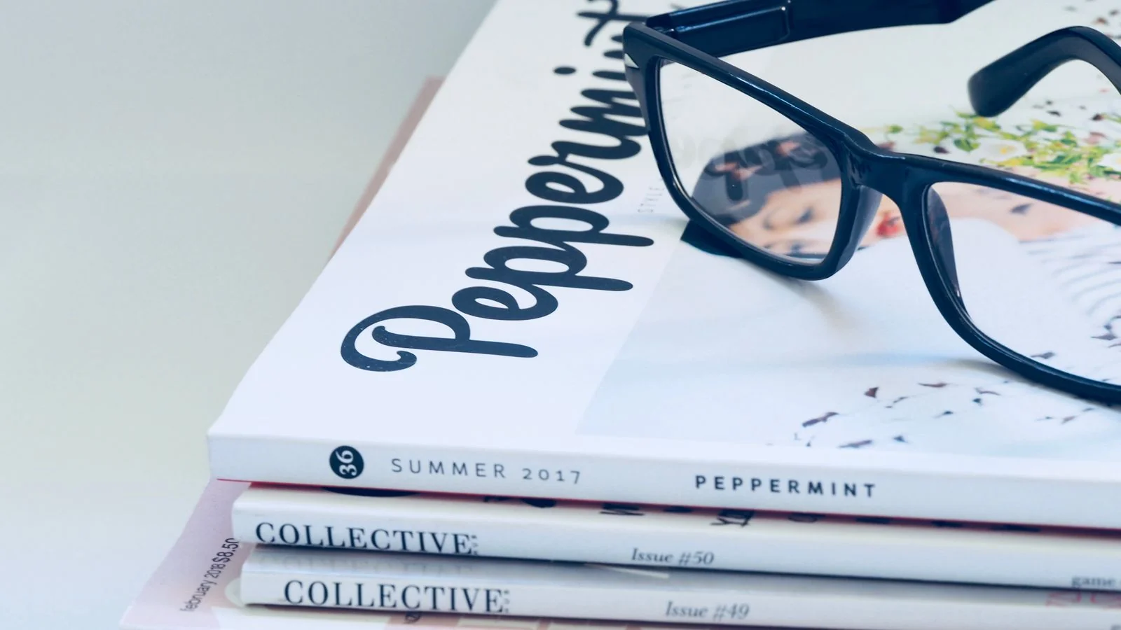 Eyeglasses resting on a stack of industry magazines, a reminder to study the publication before pitching