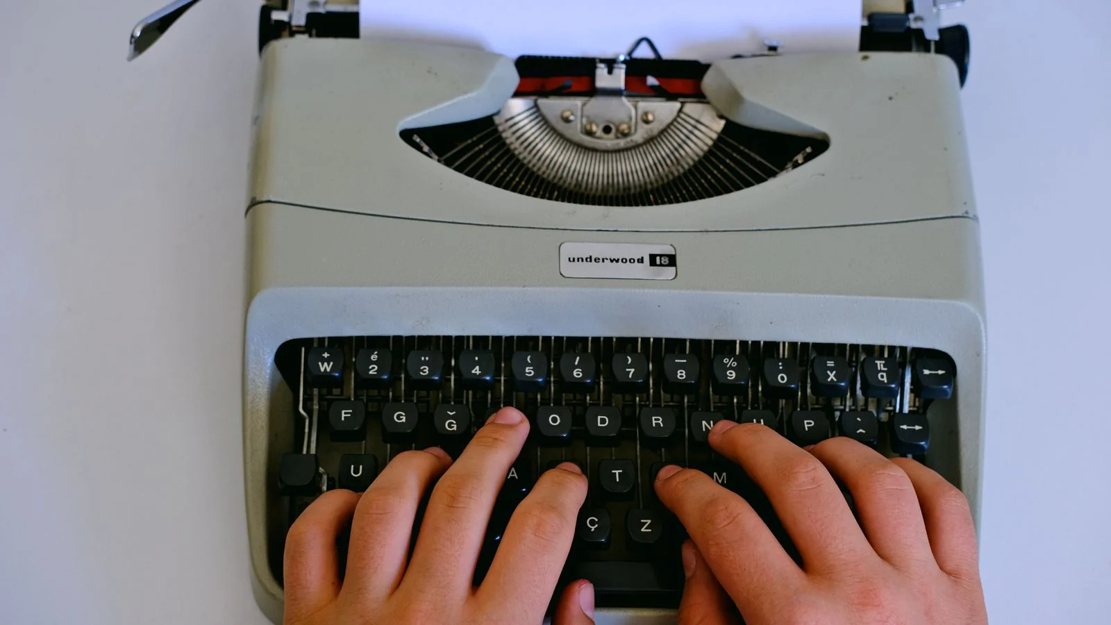 Hands typing on a typewriter, the discipline of delivering clean, finished copy a trade editor can run