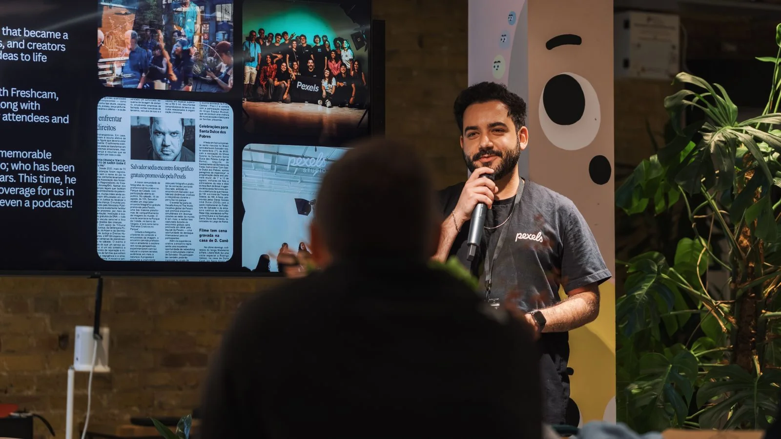 A speaker presenting to an audience from a stage, the reputation-building work that feeds Claude's corpus layer