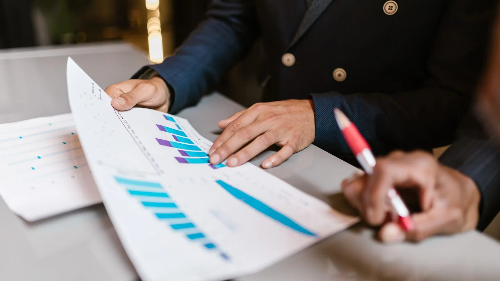 Professionals reviewing financial graphs at a meeting, the coverage-planning that decides which sub-questions you win