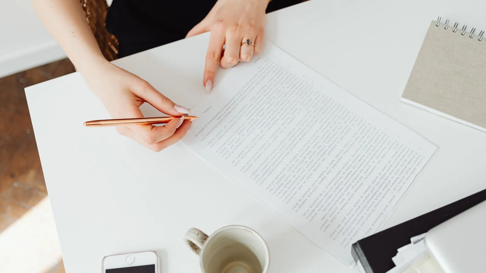 A woman reviewing a document at a white desk, refining a page to answer one precise question