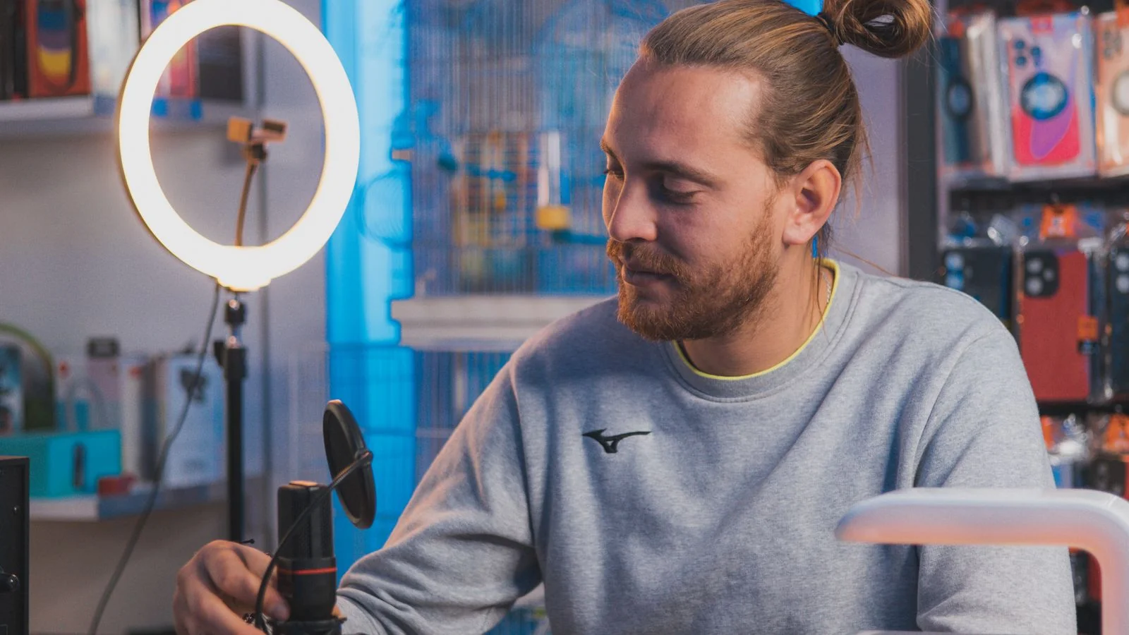 A creator adjusting a microphone in a studio, the consistent real-time presence that earns a brand Grok's attention