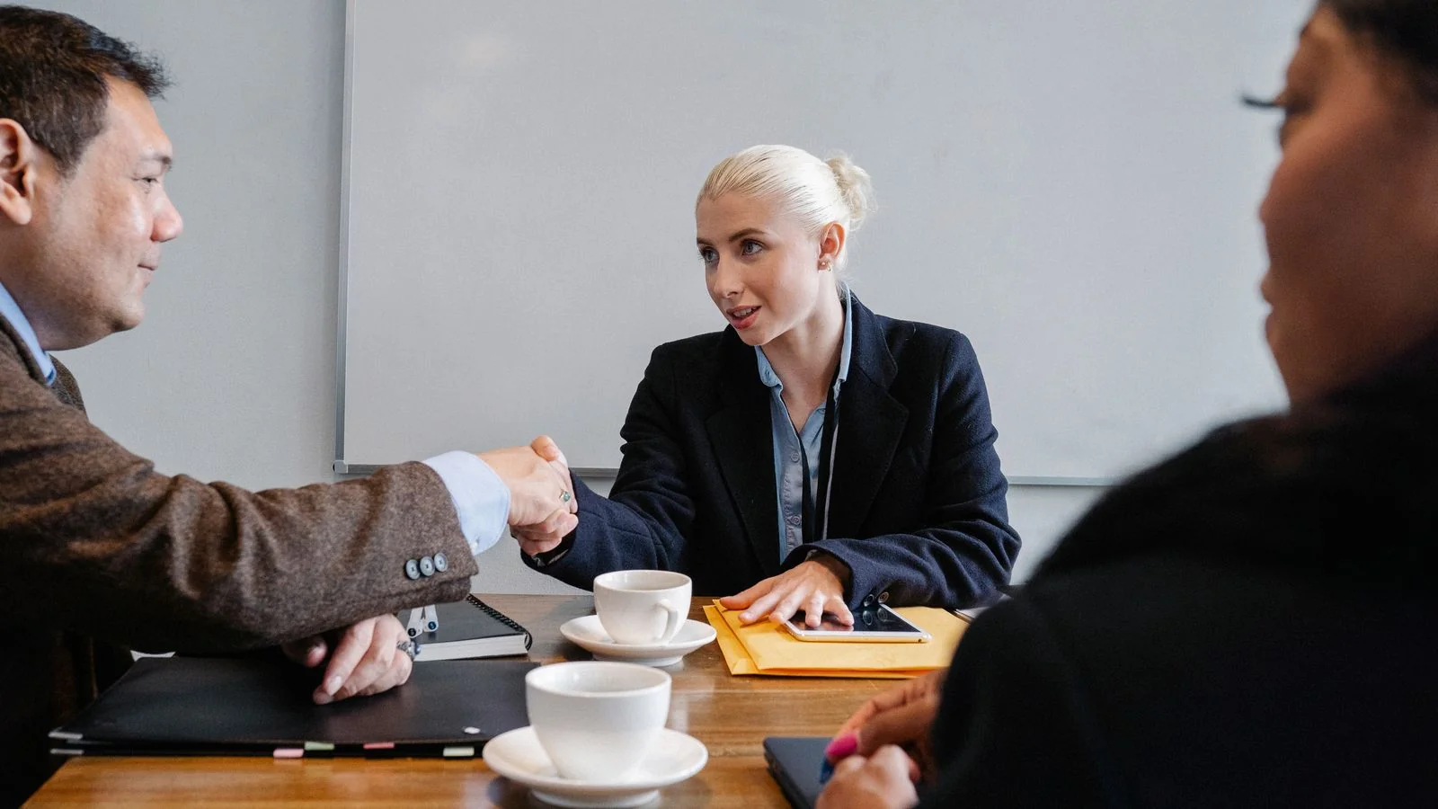 Diverse group of business professionals shaking hands around a conference table, sealing a first deal