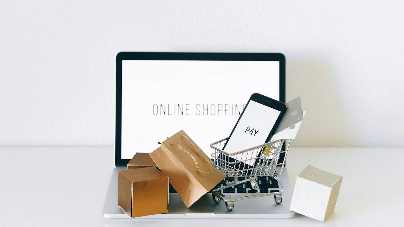 Miniature shopping cart sitting on a laptop keyboard during an online product comparison