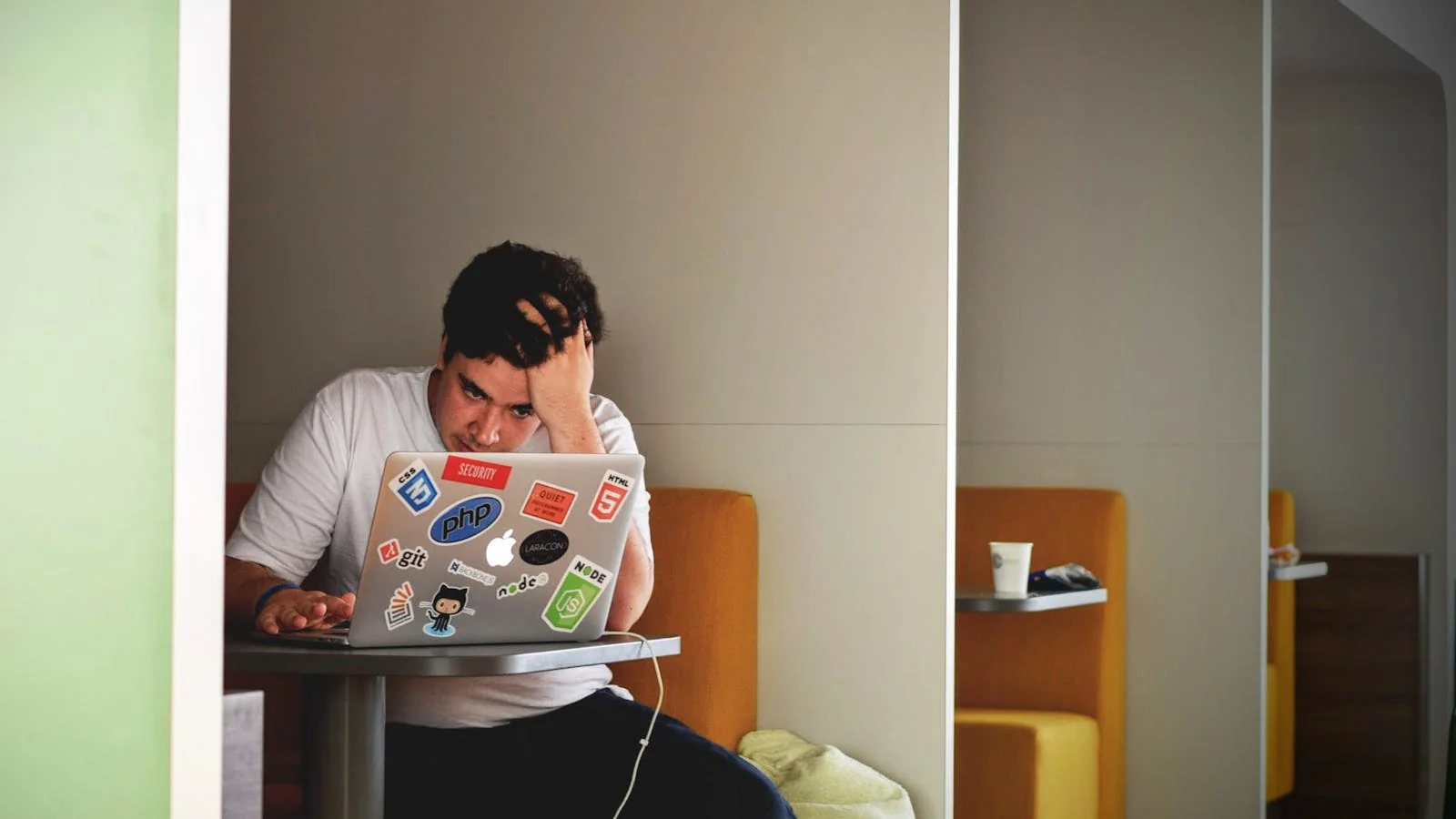 A person looking stressed while working at a laptop in a bright room