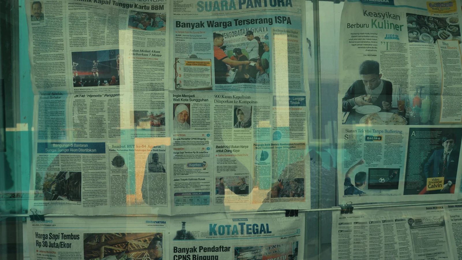 A close-up of regional newspapers stacked on a stand, each covering news specific to its local readership