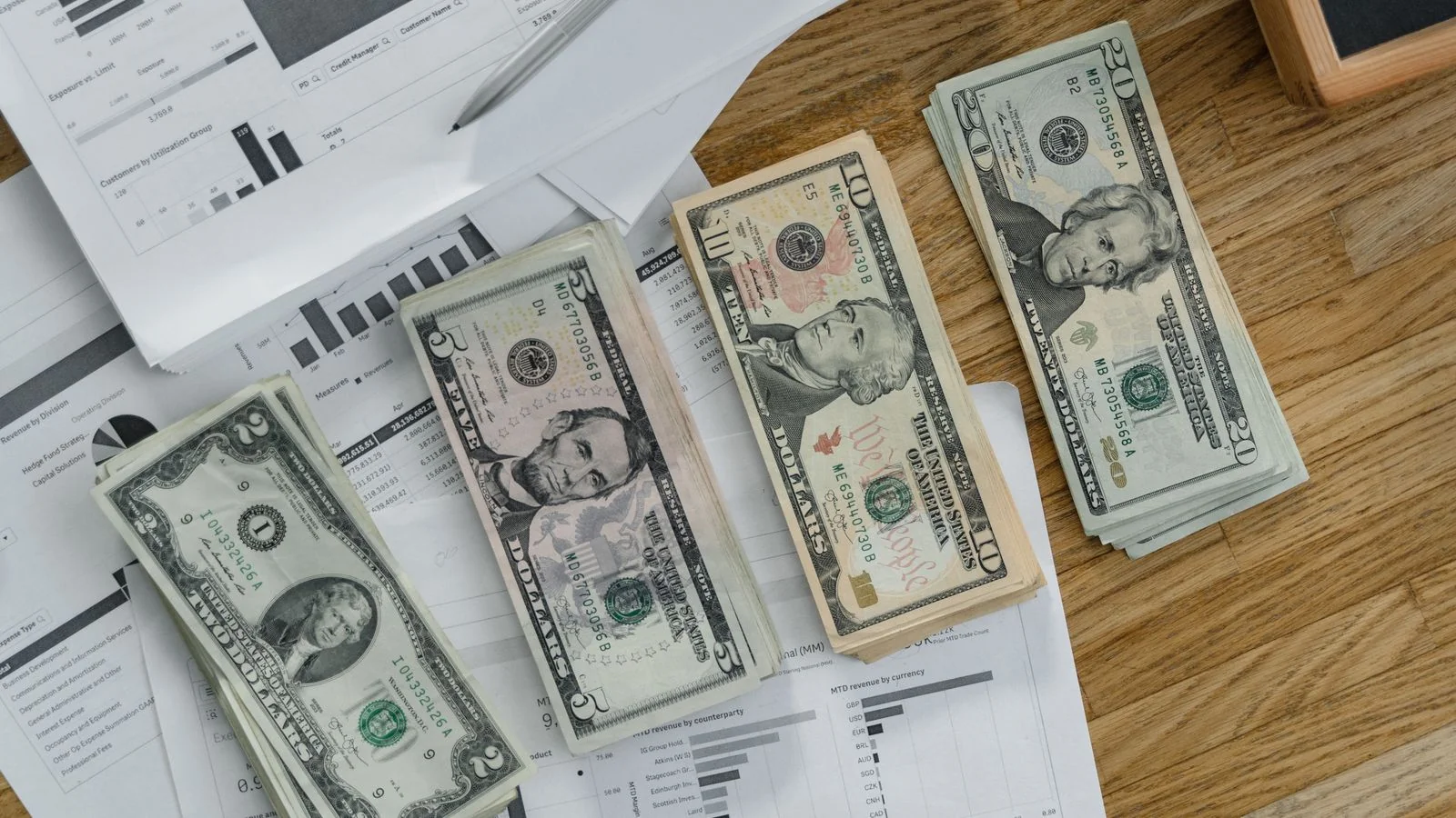 Person counting bank notes over financial documents, the gap between attention and actual revenue
