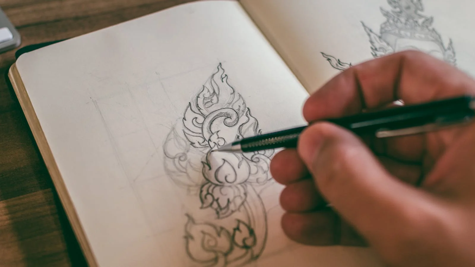 A focused founder sketching candidate company names by hand in a sketchbook with a mechanical pencil under a desk lamp.