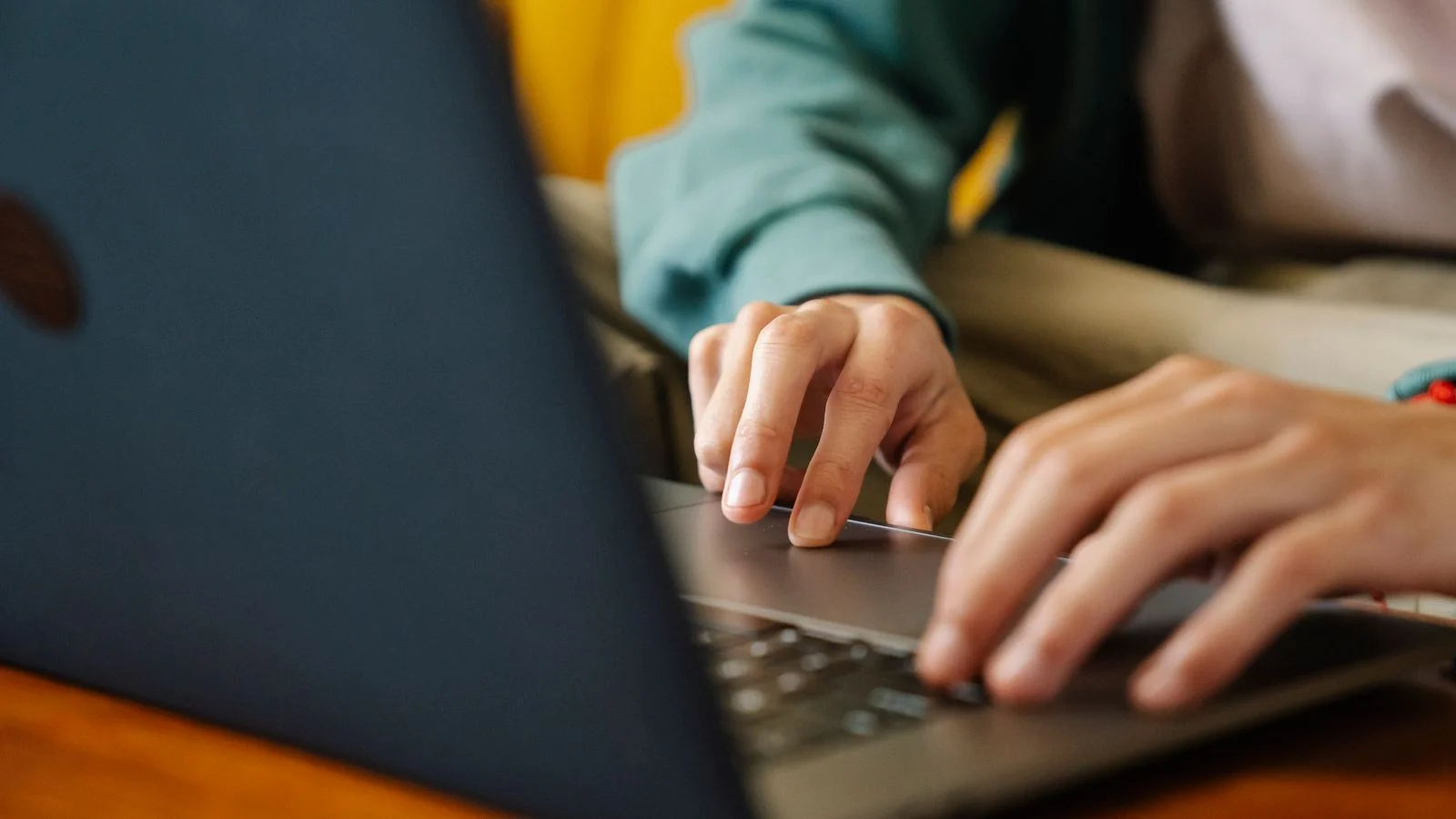 Remote worker typing at a small laptop in a plain workspace, the anonymous byline problem in one image