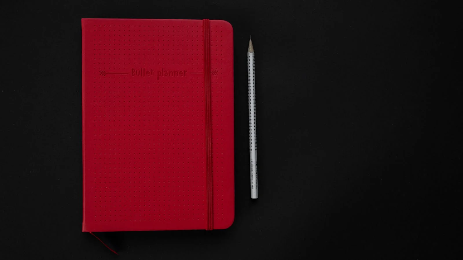 Open notebook with bullet-pointed outline next to a pen on a dark desk surface